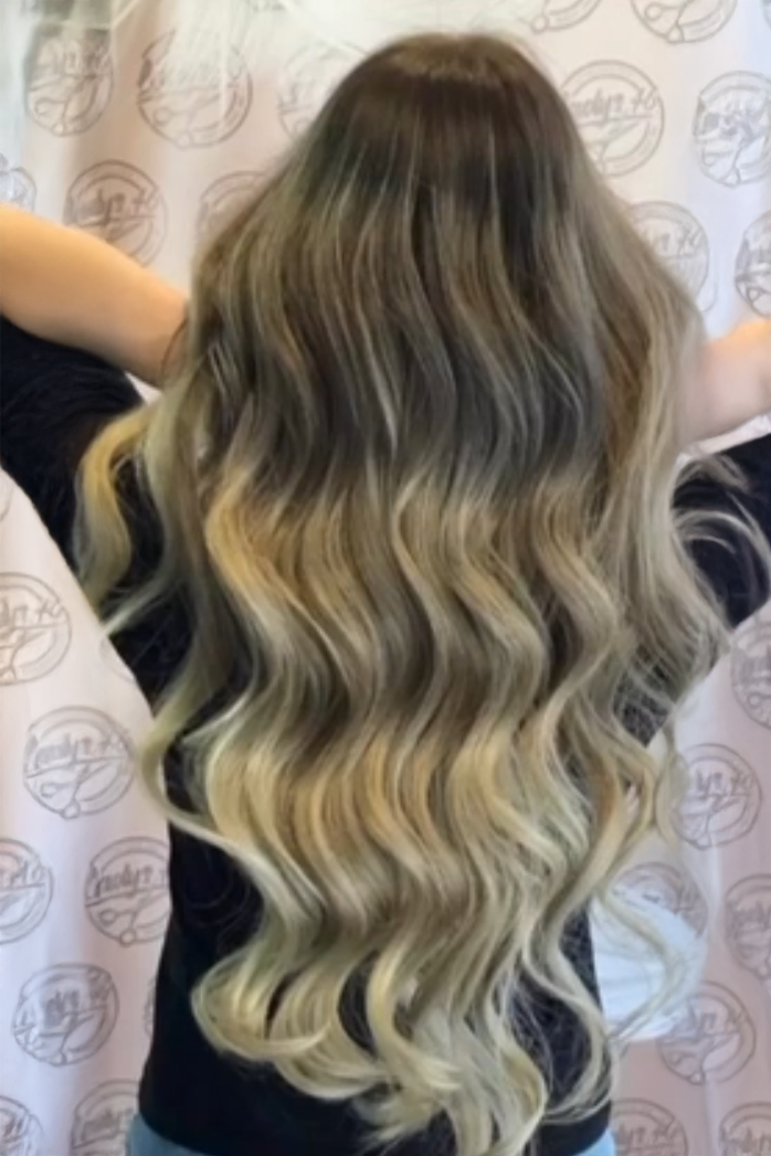 Langes, gewelltes Haar nach einer professionellen Haarverlängerung.
